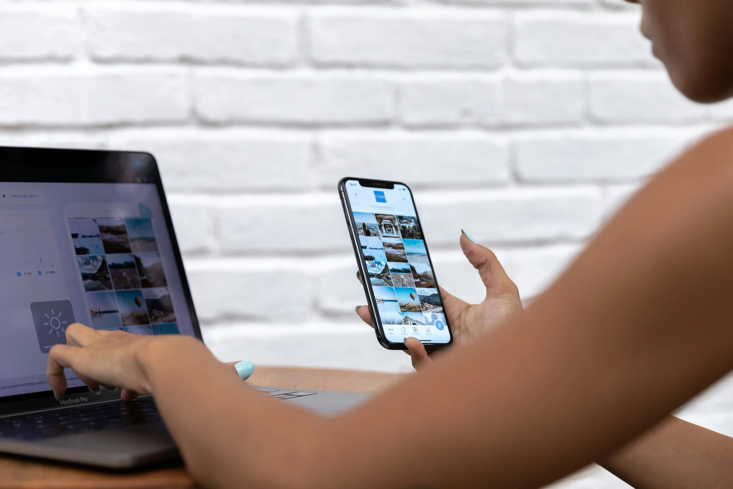 Person nutzt gleichzeitig Smartphone und Laptop an einem Schreibtisch