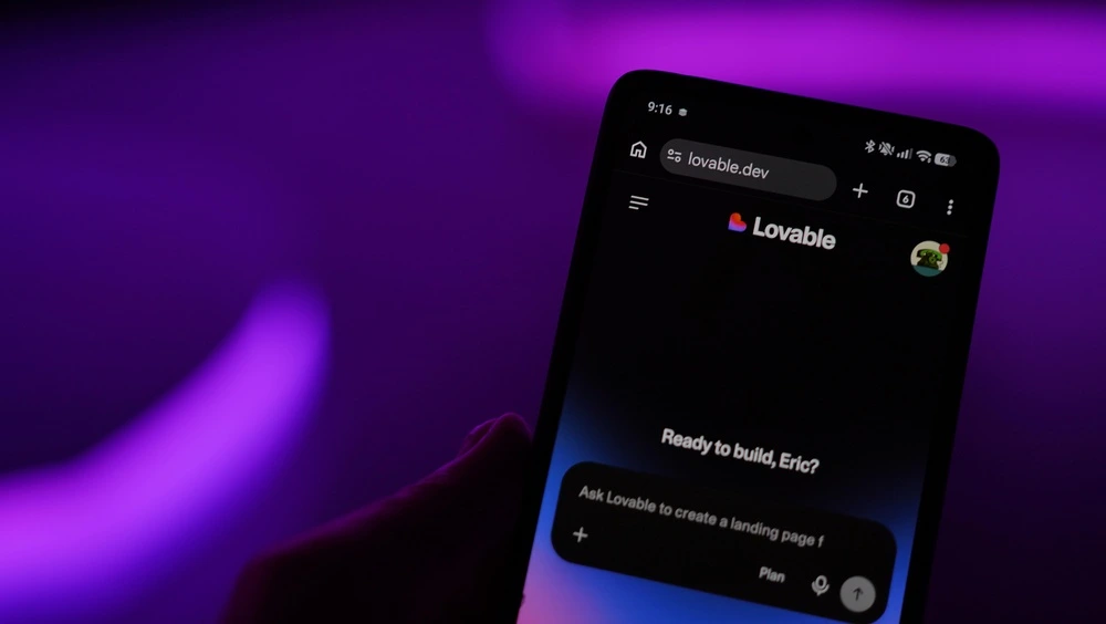 Smartphone mit geöffneter Lovable-Weboberfläche auf lovable.dev vor violettem Hintergrund
